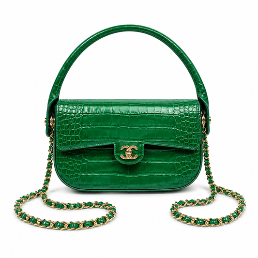 A green crocodile-embossed leather handbag with a top handle, gold-tone interlocking CC clasp, and a green-and-gold chain strap, shown on a plain white background.