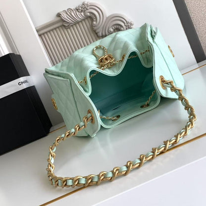 Light blue handbag with gold chain strap on a white surface